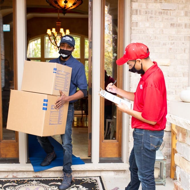 Mighty Moving crew carrying moving boxes out of a house
