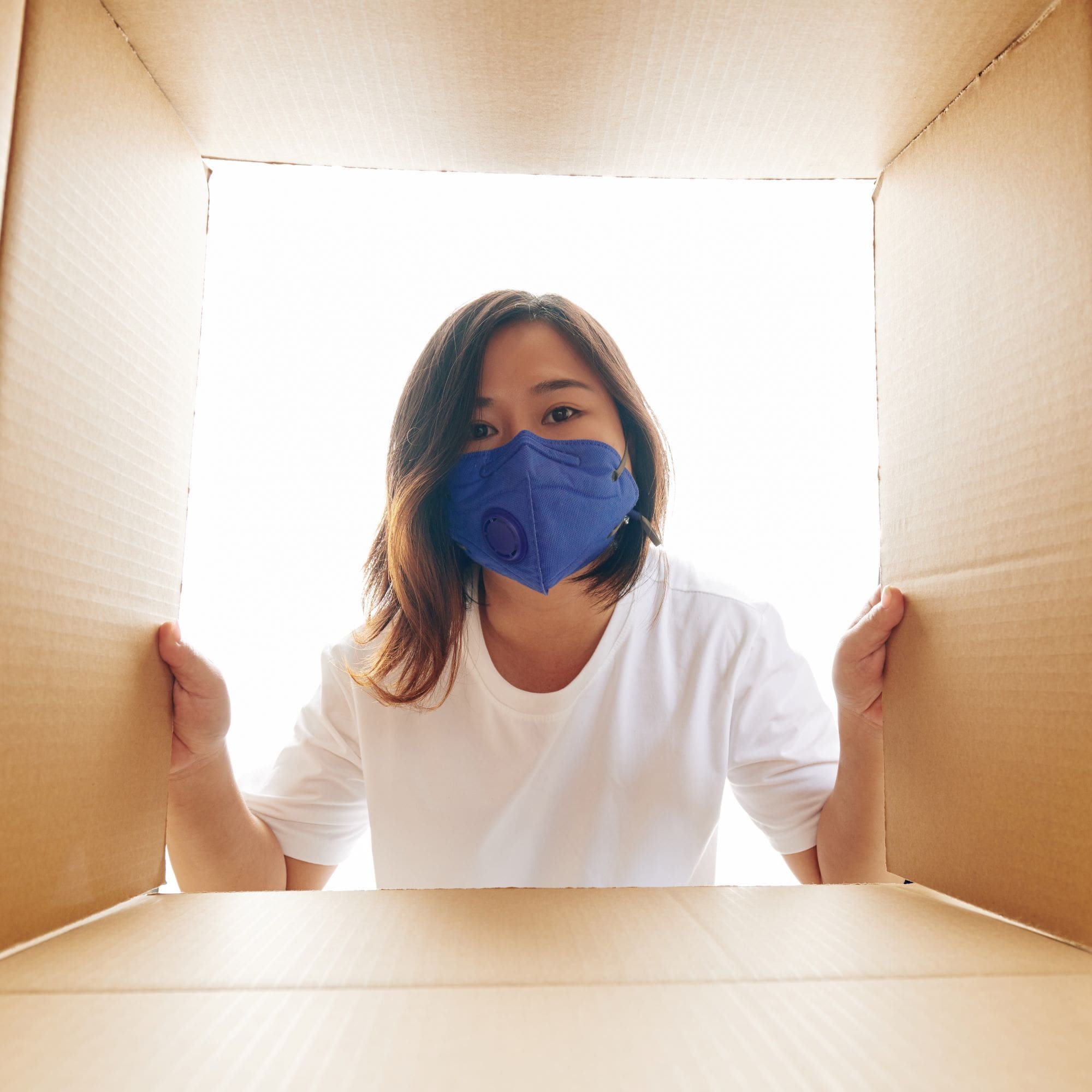 Woman in a mask unpacking a box