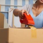 Woman sealing a moving box with tape