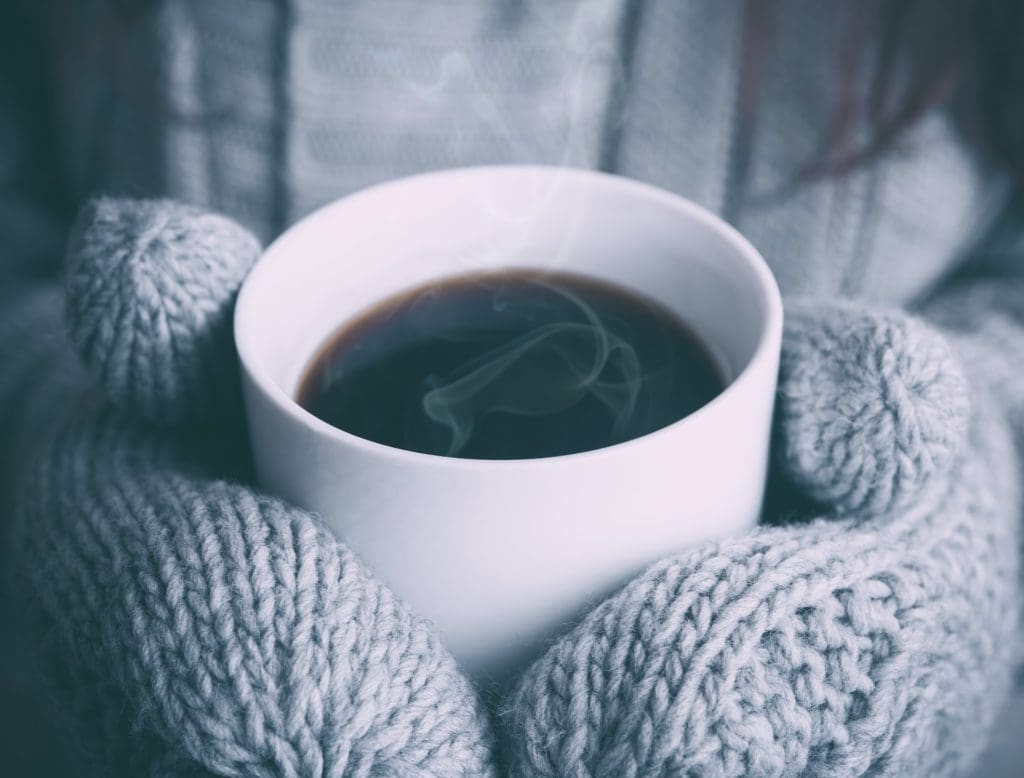 Holding a cup of hot coffee with gloves